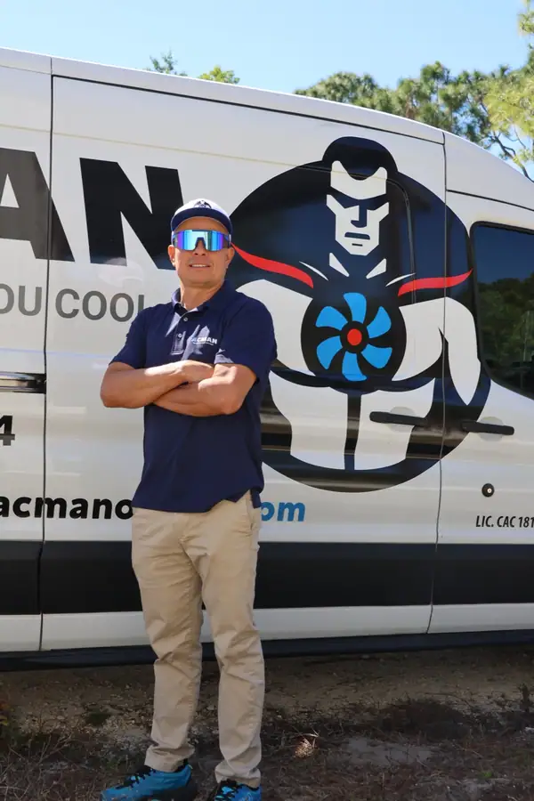 An ACMAN technician with arms crossed in front of the superhero on the van