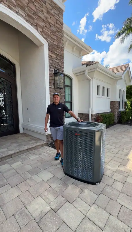 An ACMAN technician moving a new condenser into place at a home